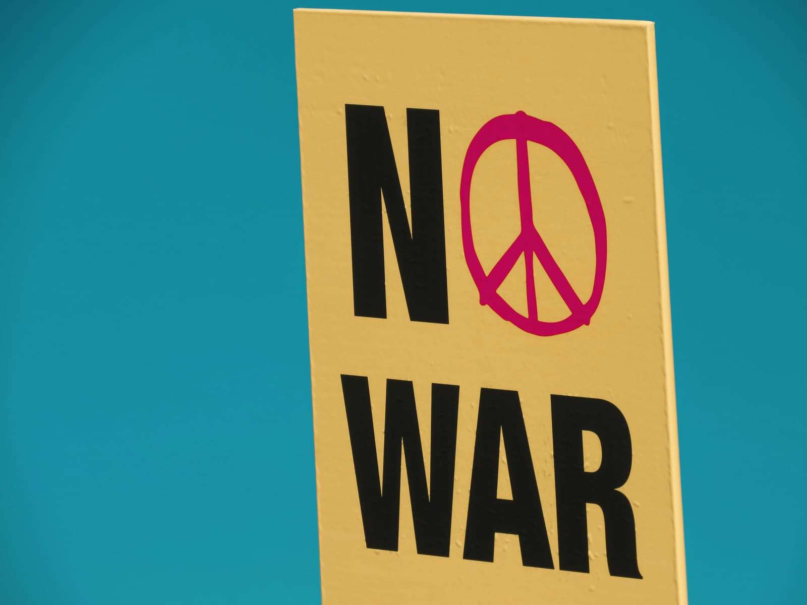 A yellow poster reading “No war” with a peace sign